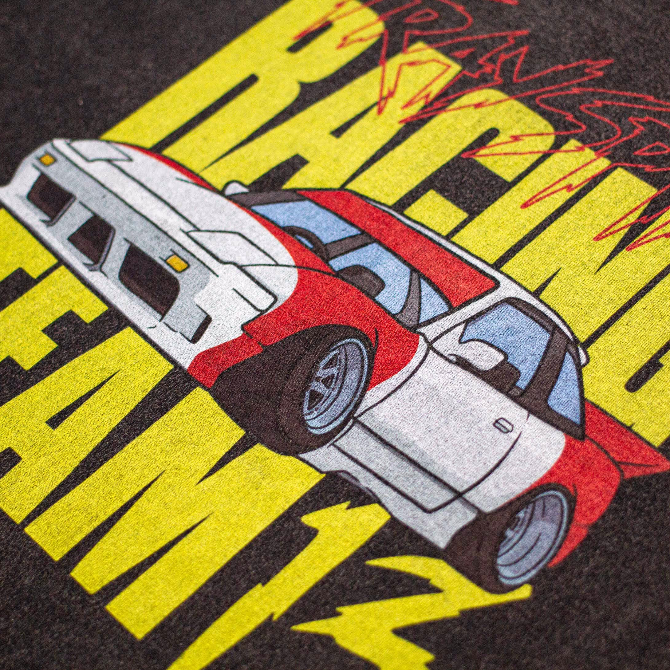 Close-up look of the large, digital print on the back of Straygang's black wash t-shirt. It features an illustrative print of a drift car accompanied by the words 'Strayspirit racing team 13'.