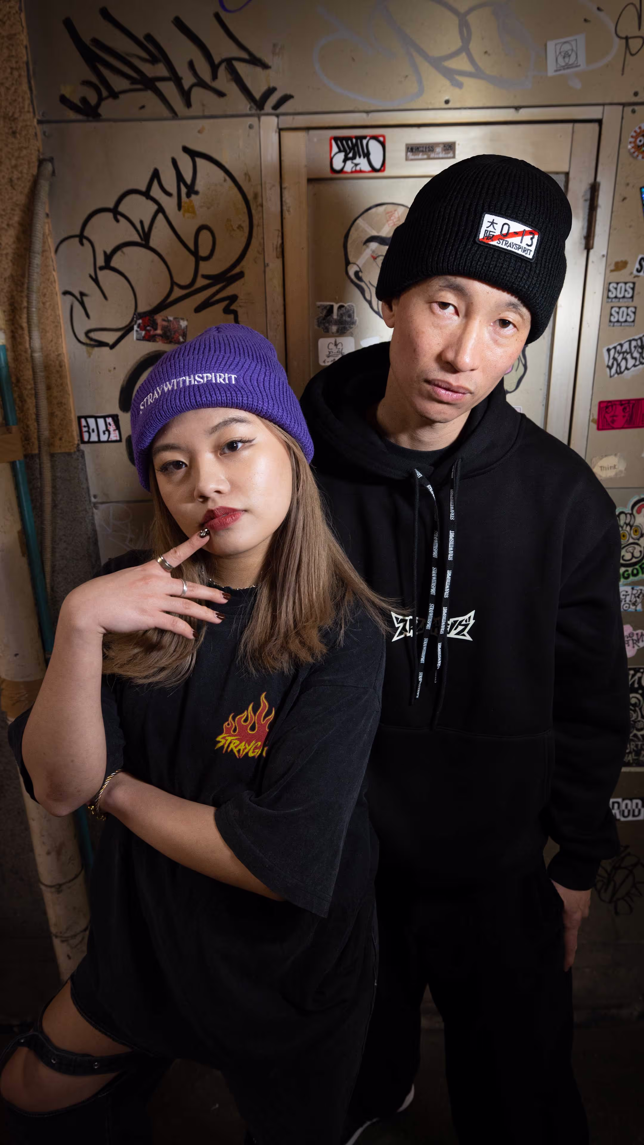 Two people in the streets of Tokyo wearing Straygang branded clothing. 